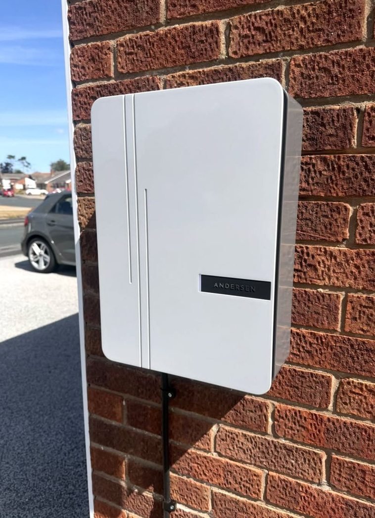 White EV charger on a brick gable
